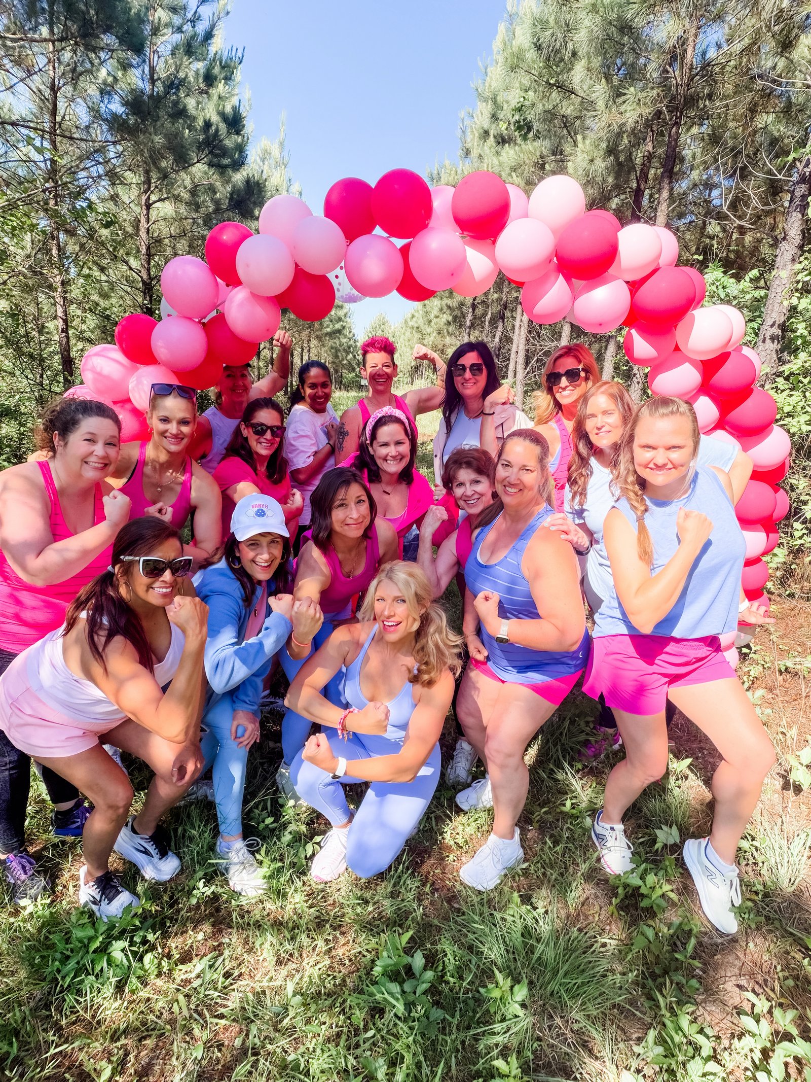 Vary-8 women flexing under a pink balloon arch
